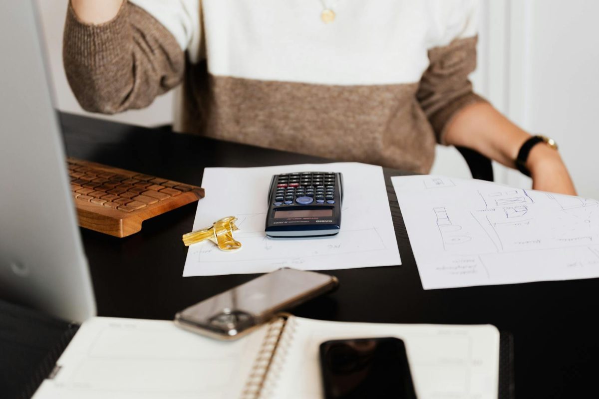 Tout savoir sur la comptabilité en ligne A business desk setup with a calculator, papers, and a keyboard, reflecting a work environment.