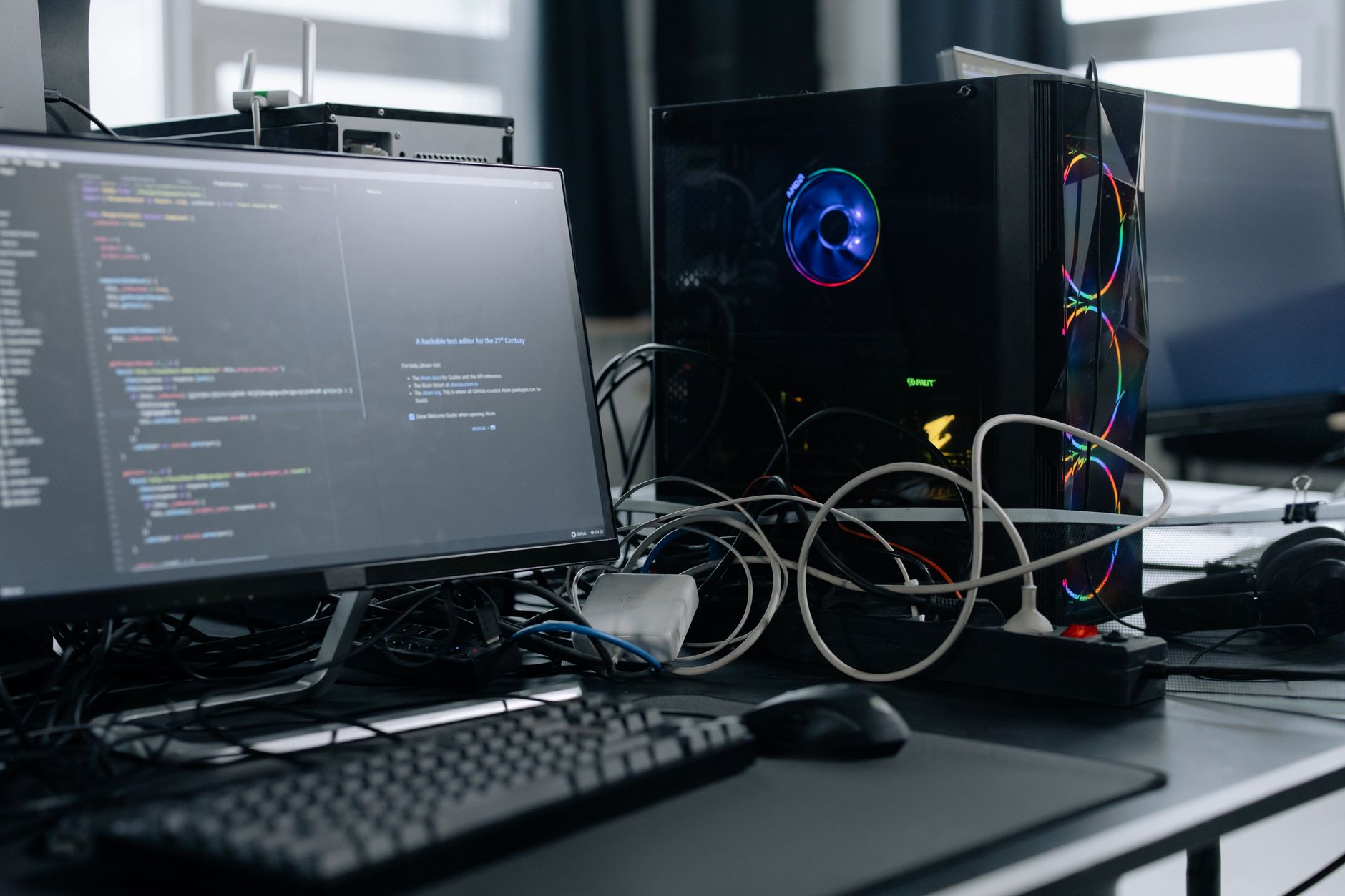 Un espace de travail moderne avec un écran d'ordinateur affichant du code, une tour PC et des périphériques.