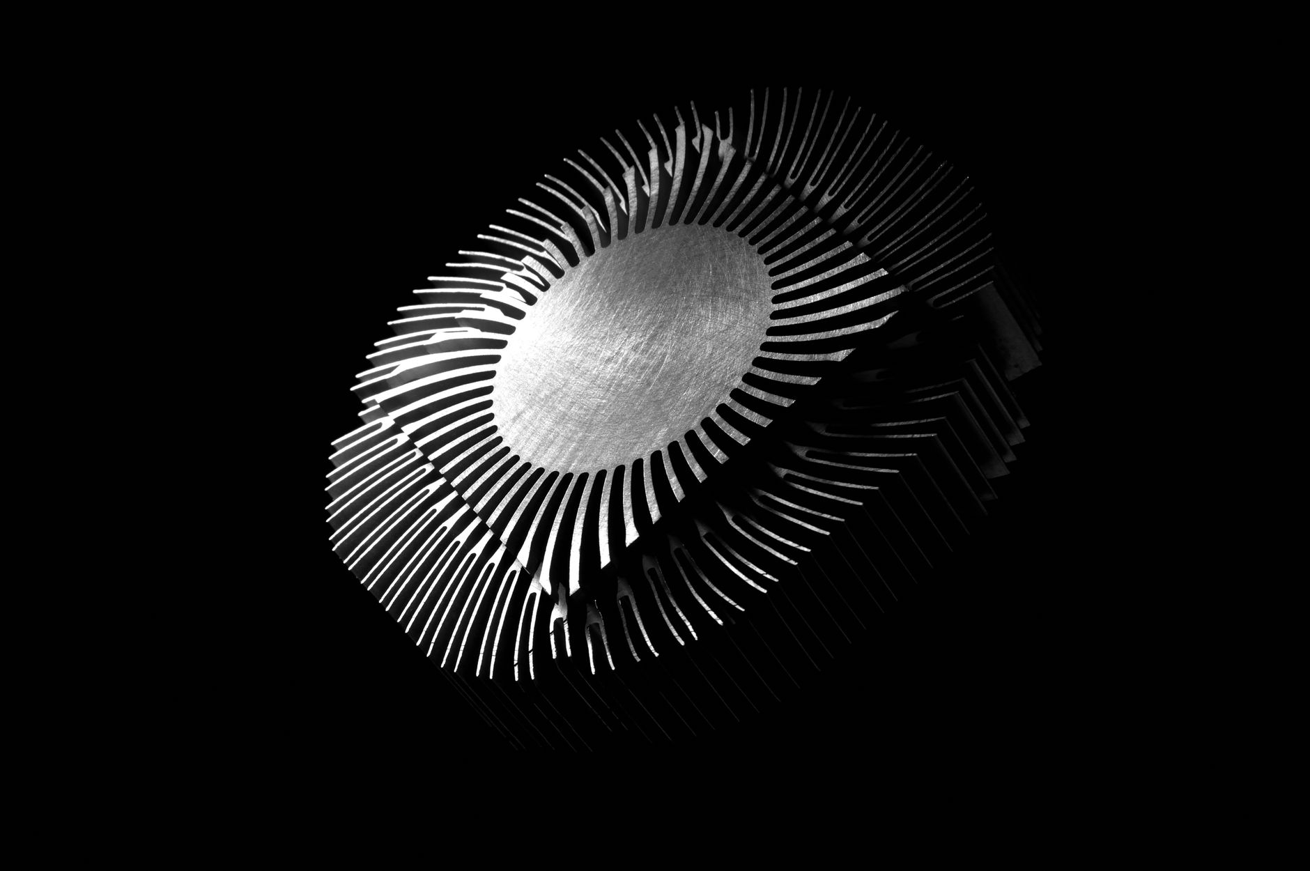 Gros plan abstrait d'un dissipateur thermique métallique aux motifs complexes sur fond noir.