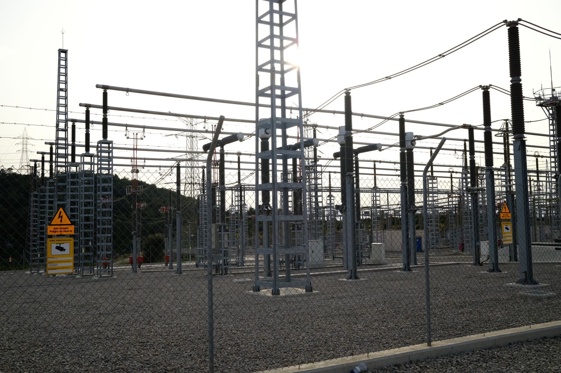 Sous-station électrique extérieure avec équipement haute tension et panneaux de sécurité, entourée de clôtures.